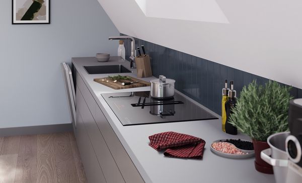 Perspective angulaire d'un aménagement de cuisine sous un toit en pente avec une table de cuisson Bosch avec module de ventilation intégré.