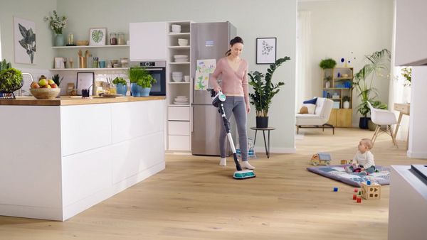 Ein Video, das eine Frau bei der Reinigung des Hartbodens eines Wohnraums mit dem Bosch Unlimited 7 ProHygienic Aqua zeigt und die automatische Wasserdosierung erklärt.