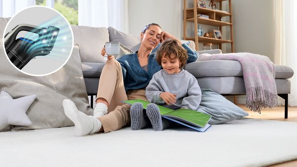 A woman and a child seated on the floor, engaged with a book, sharing a moment of learning and connection.
