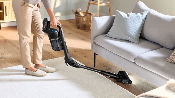 A woman efficiently cleans her living room with an Unlimited 10 cordless vacuum cleaner.