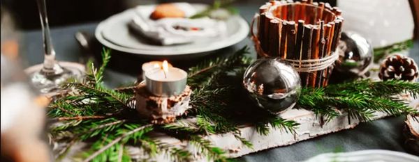 Christmas dinner table with fresh plant centrepiece and out of focus plate in the background