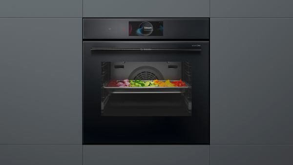 Bosch Serie 8 accent line dampovn, i den er en bageplade med forskellige grøntsager.
