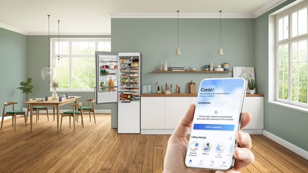 Smartfon z otwartą aplikacją Home Connect w nowoczesnej kuchni z różnymi urządzeniami gospodarstwa domowego marki Bosch.