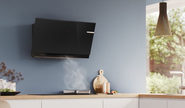 A modern kitchen featuring a black wall-mounted sleek hood above the cooking area.