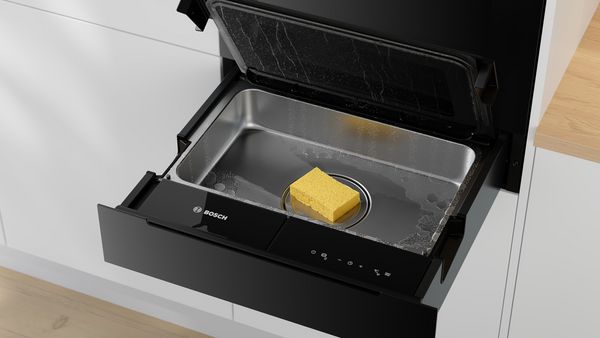 Sertar termic Bosch deschis parţial, cu un burete în interior, evidenţiind suprafaţa interioară din oţel inoxidabil.