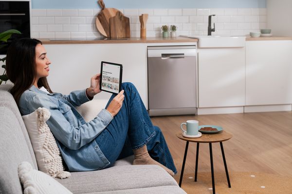 Cuisine moderne avec tablette affichant les commandes de la maison intelligente, la tasse à café et les appareils électroménagers.