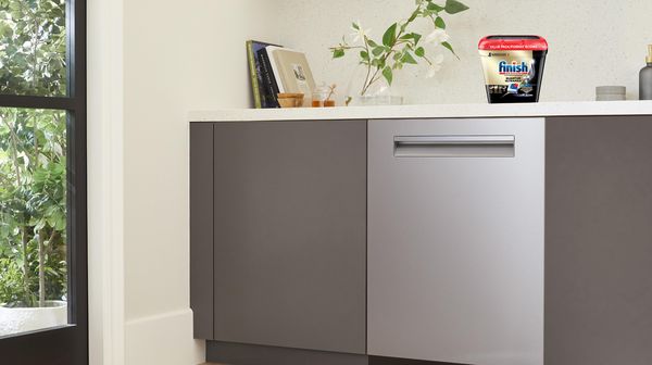 Modern kitchen with a Finish Quantum Ultramax container on the countertop beside a dishwasher.