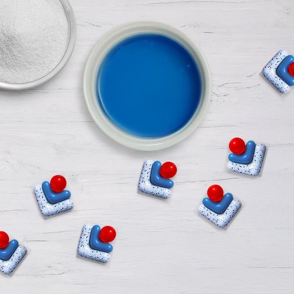Dishwasher tabs, liquid dishwasher detergent and powder detergent on a light surface.