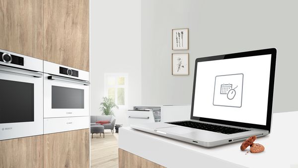 Nowoczesna drewniana kuchnia ze sprzętem AGD, a na blacie znajduje się laptop z ikoną bezpośredniej rezerwacji zamówień.