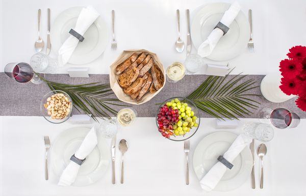 Zu einem perfekt gedeckten Tisch gehören Wein, Brot, dekoratives Geschirr und Blumenschmuck.