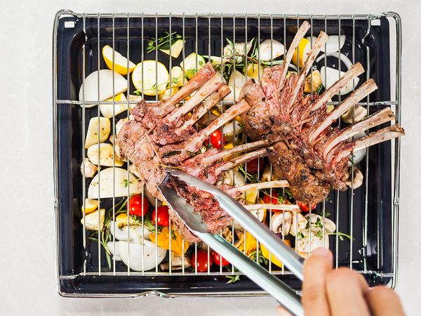 Placing a wire rack on the tray of vegetables, after which the seared lamb rack is layed on top