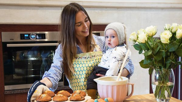Woman holding her child whilst baking muffins