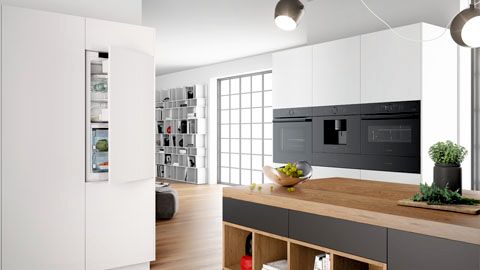Cucina moderna in bianco, con elettrodomestici Bosch e piano in legno con grappoli d'uva. Frigorifero con porta socchiusa.