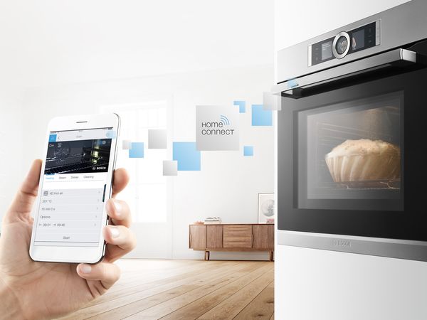 Smartphone with Home Connect on screen. Home connect icons in squares float towards Bosch oven in which a cake bakes.