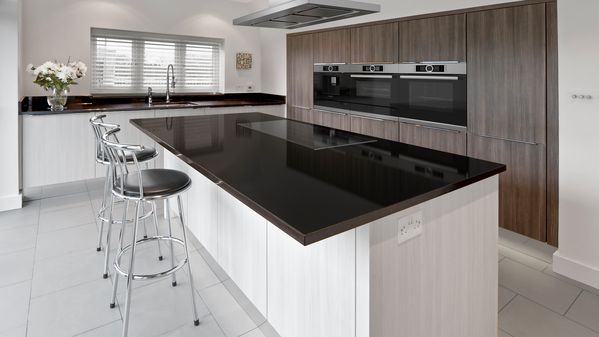 Prostorná kuchyň ve tvaru U s velkými nerezovými kuchyňskými spotřebiči a klasickými bílými skříňkami doplněnými elegantními římsami u stropu