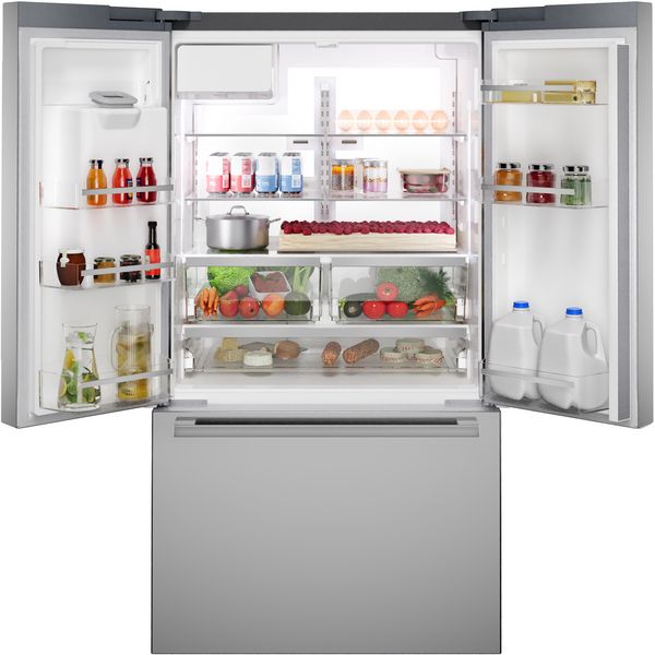 Réfrigérateur à porte française ouverte, rempli d'aliments frais, de boissons et de tablettes bien organisées.