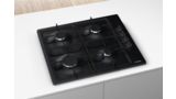 Черная варочная поверхность Bosch Серии 2 с 4 конфорками в центре узкого белого острова на кухне.
