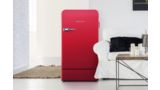 Red freestanding Bosch fridge in a modern room next to sofa and coffee table.