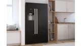 Black freestanding Bosch fridge with two large doors in a bright modern kitchen.