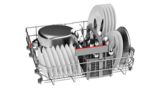 A bottom dishwasher rack with a cutlery basket full of a pot and tableware.