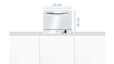 Mini lave-vaisselle Bosch blanc sur un plan de travail dans une cuisine blanche.