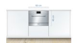 Built-in, compact 60 cm wide Bosch dishwasher in stainless steel integrated into a white kitchen.