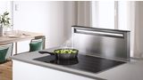 Daudz vietas ēdiena gatavošanai: liela indukcijas gatavošanas virsma, kas apvienota ar lejupvilkmes ventilāciju mājīgā virtuvē ar ēdamgaldu