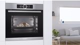 A must-have for baking enthusiasts: a built-in steam oven with a loaf of bread inside, installed at eye level in an open plan kitchen