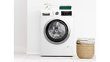 Fritstående, frontbetjent vaskemaskine fra Bosch i et moderne, hvidt badeværelse