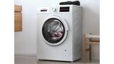Ένα πλυντήριο ρούχων SlimLine εμπρόσθιας φόρτωσης Bosch σε ένα μοντέρνο λευκό μπάνιο