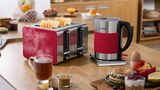 Frühstückstisch mit Silikonset. Wasserkocher und 4-Schlitz-Toaster in Edelstahl und Rot. 