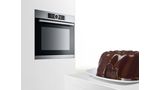 A chocolate cake in front of a Bosch oven in a modern white kitchen.