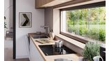 Leņķa skats uz virtuvi, kurā zem loga atrodas Bosch plīts virsma ar integrētu ventilācijas moduli.