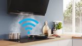 Symbol Wi-Fi nałożony na zdjęcie płyty grzewczej i okapu kuchennego w nowoczesnej kuchni pokazujący, że te dwa urządzenia są połączone.
