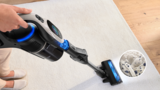 A Bosch vacuum cleans dirt from the floor. Behind it are dirty rubber boots.