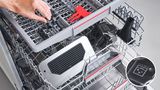 Κάποιος τοποθετεί εξαρτήματα της μηχανής καφέ στο πλυντήριο πιάτων, δείχνοντας ότι είναι κατάλληλα για το πλυντήριο πιάτων.