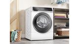 Een moderne wasruimte met een witte wasmachine en droger, met vers opgehangen kleren en een rieten mand gevuld 