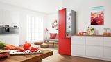 Réfrigérateur rouge pose-libre Bosch dans une pièce moderne à côté d'un canapé et d'une table basse.