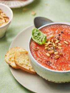 Small bowl of gazpacho garnished with pine nuts and basil. 