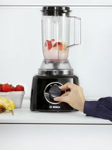 Person turning settings dial to blend fruit inside