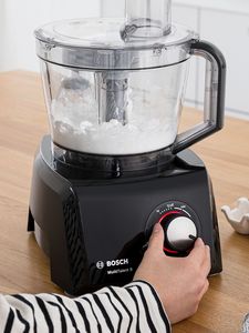 Person moving settings dial to whip ingredients inside food processor