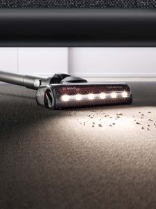 Eine Person saugt den Boden mit einem Bosch Staubsauger mit LED Beleuchtung.