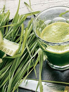 Svež zeleni sok sa biljem i kriškama krastavca pored njega.
