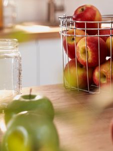 Zelena in rdeča jabolka v košari na kuhinjskem pultu.