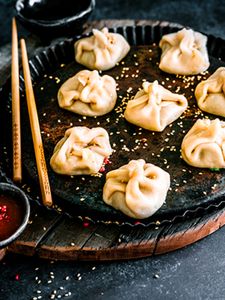 Perfectly shaped dumplings on a black plate with a dip on the side. 