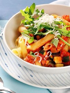  A bowl filled with ratatouille penne with rocket and parmesan cheese.