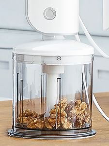 A detailed view of the chopper of the Bosch hand mixer with walnuts in it.