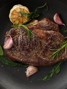 Perfectly cooked steak in a pan with garlic, herbs and lemon.