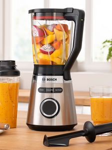 VitaPower Series 4 blender filled with yellow and orange fruits placed together with filled glasses and ToGo bottle on kitchen table.