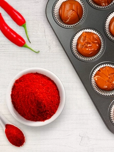 A small bowl of hot pepper placed next to a muffin rack.